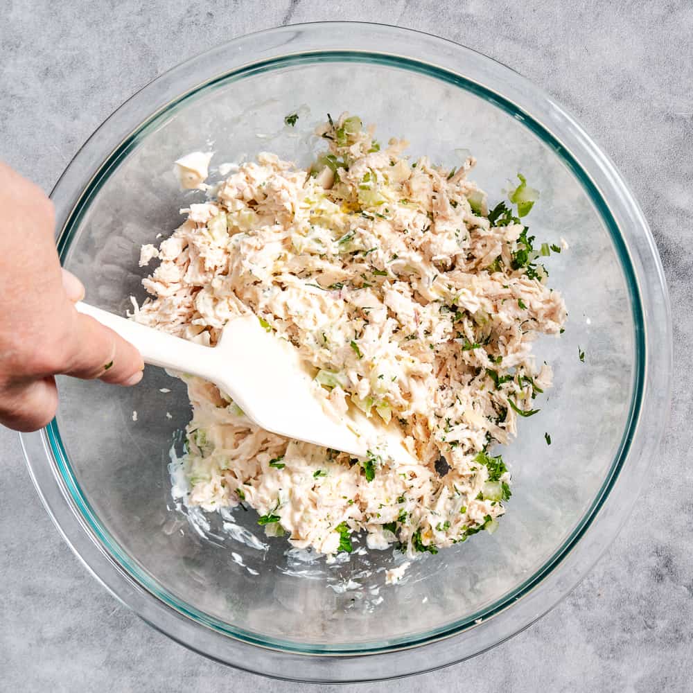 A white mixing bowl of creamy chicken salad.