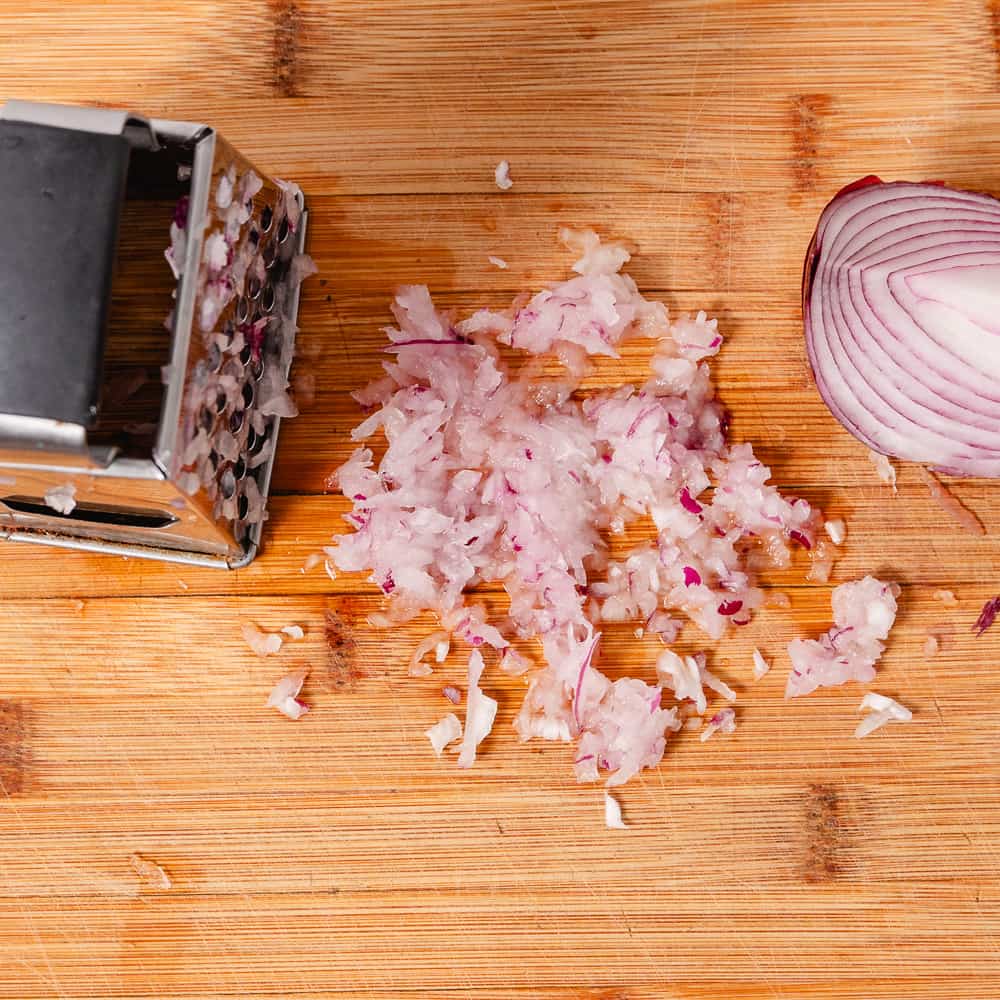 How to grate a red onion on a box grater.