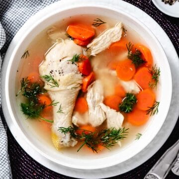 chicken soup with carrots and parsley in a bowl with spoons.