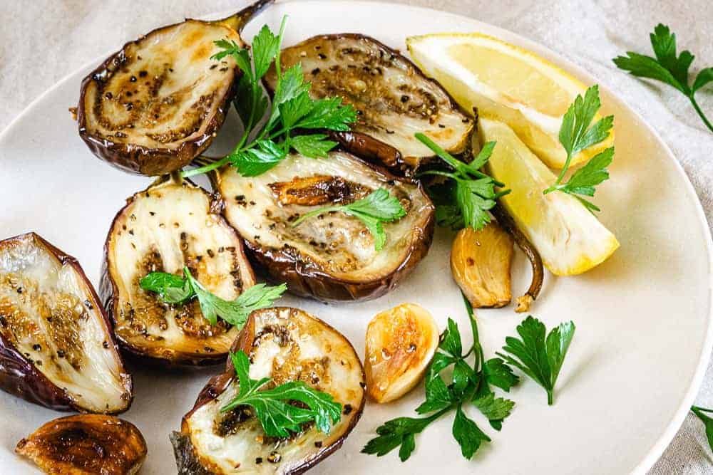 Roasted baby eggplant with garlic on a plate.