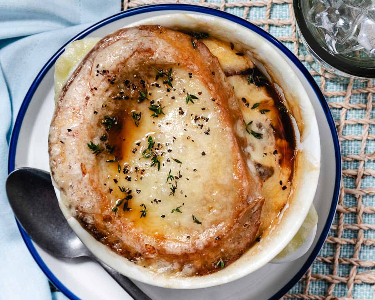 Close-up of homemade onion soup with a golden cheese crust and herbs sprinkled on top.