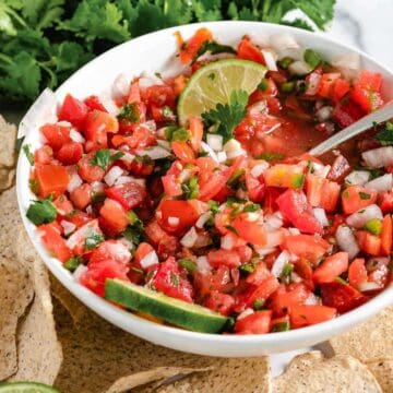 Pico de Gallo in a white bowl surrounded by Siete tortilla chips.