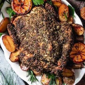 Roasted chicken on a platter with potatoes and lemons