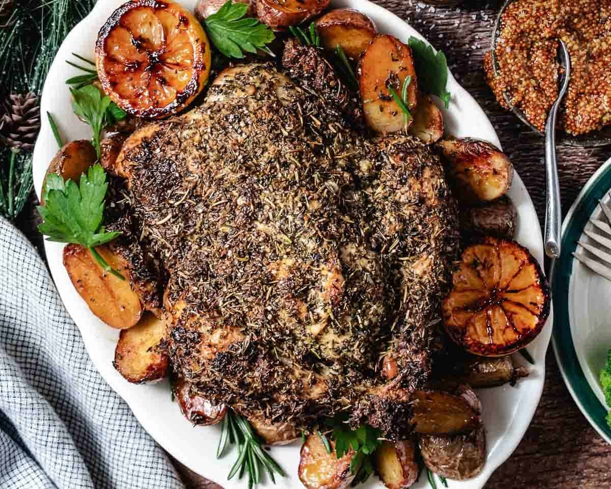 whole roasted chicken coated with herbs surrounded by lemons