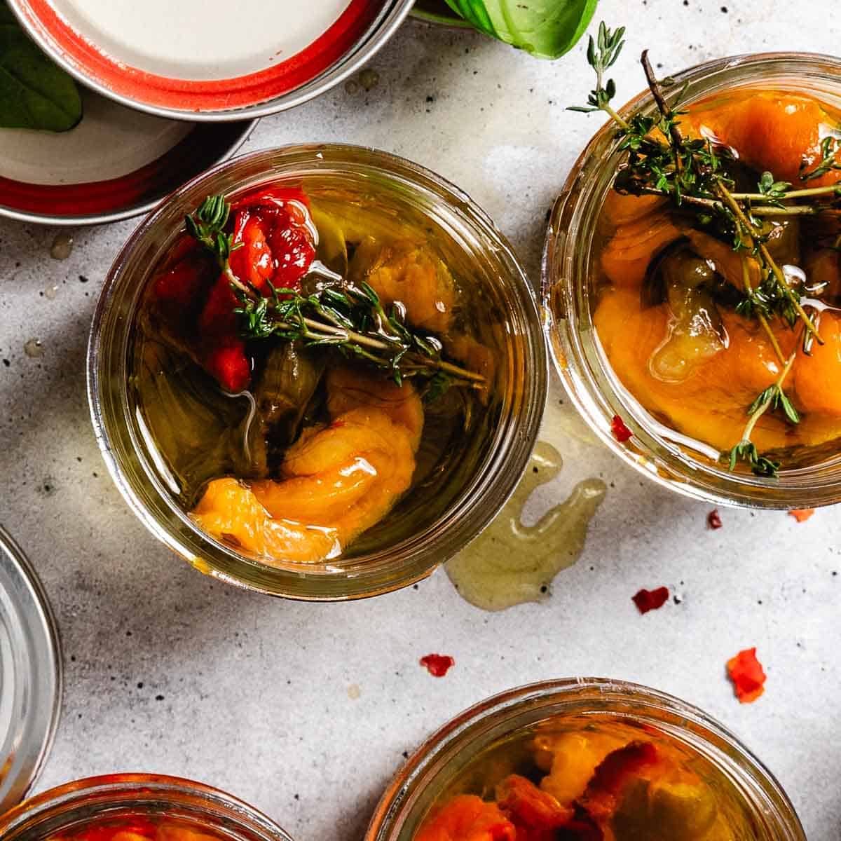Roasted peppers with herbs in mason jars.