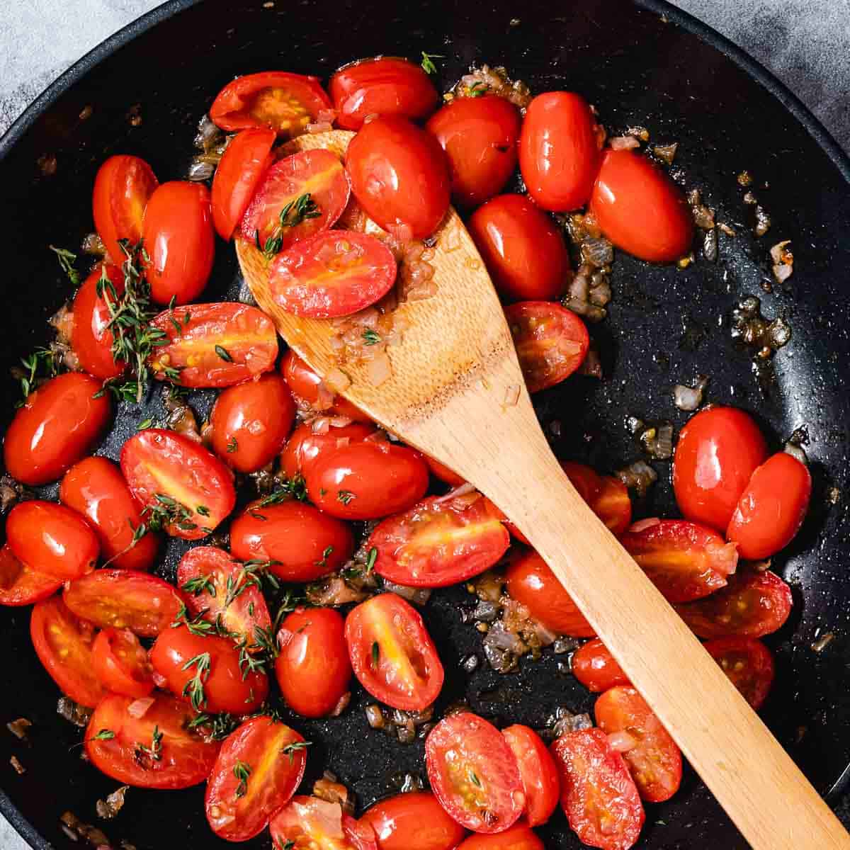 tomatoes and shallots in a black skillet.