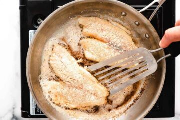 Yellowtail snapper cooking in skillet.