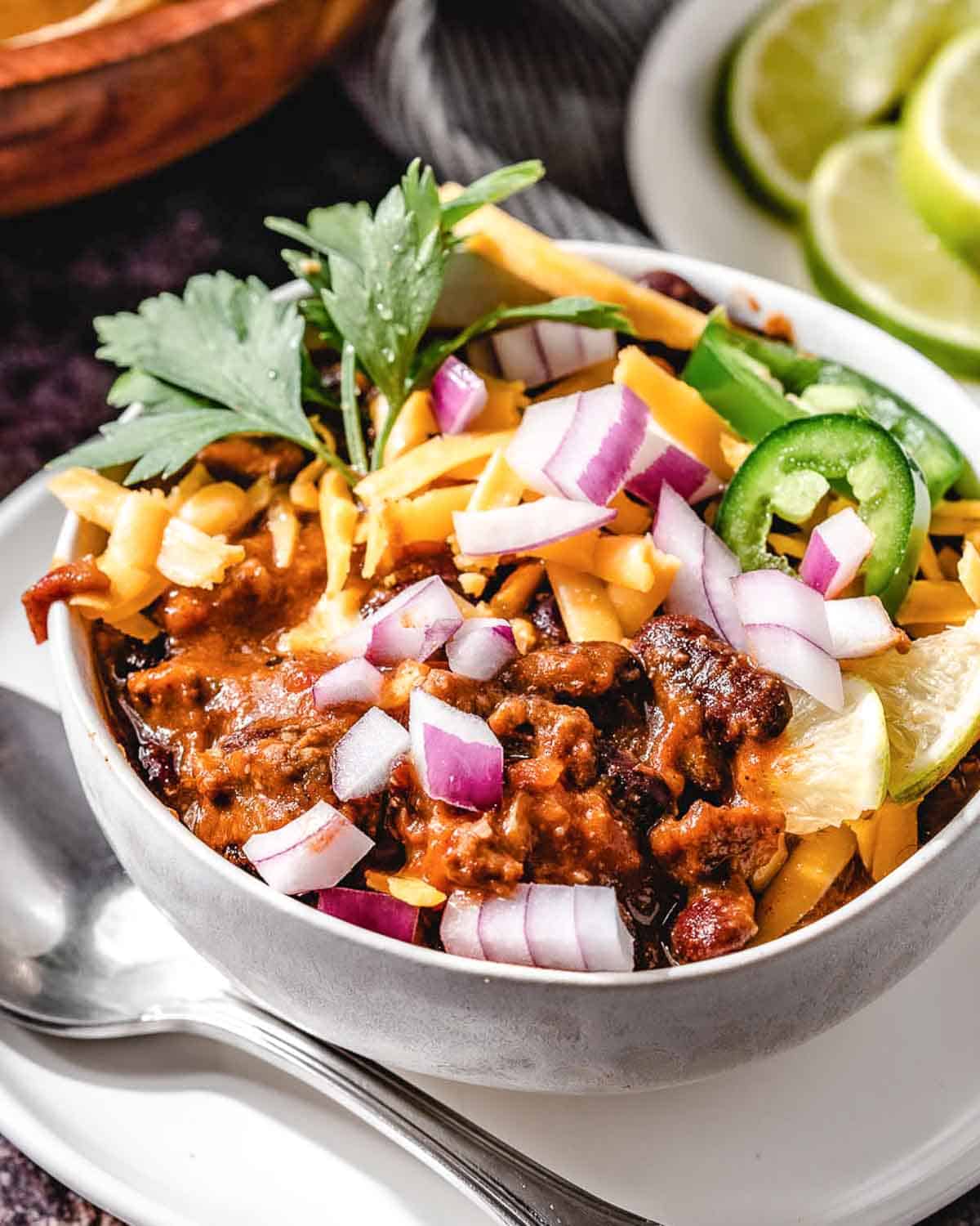 beef and bean chili with cheese and onions in a bowl.