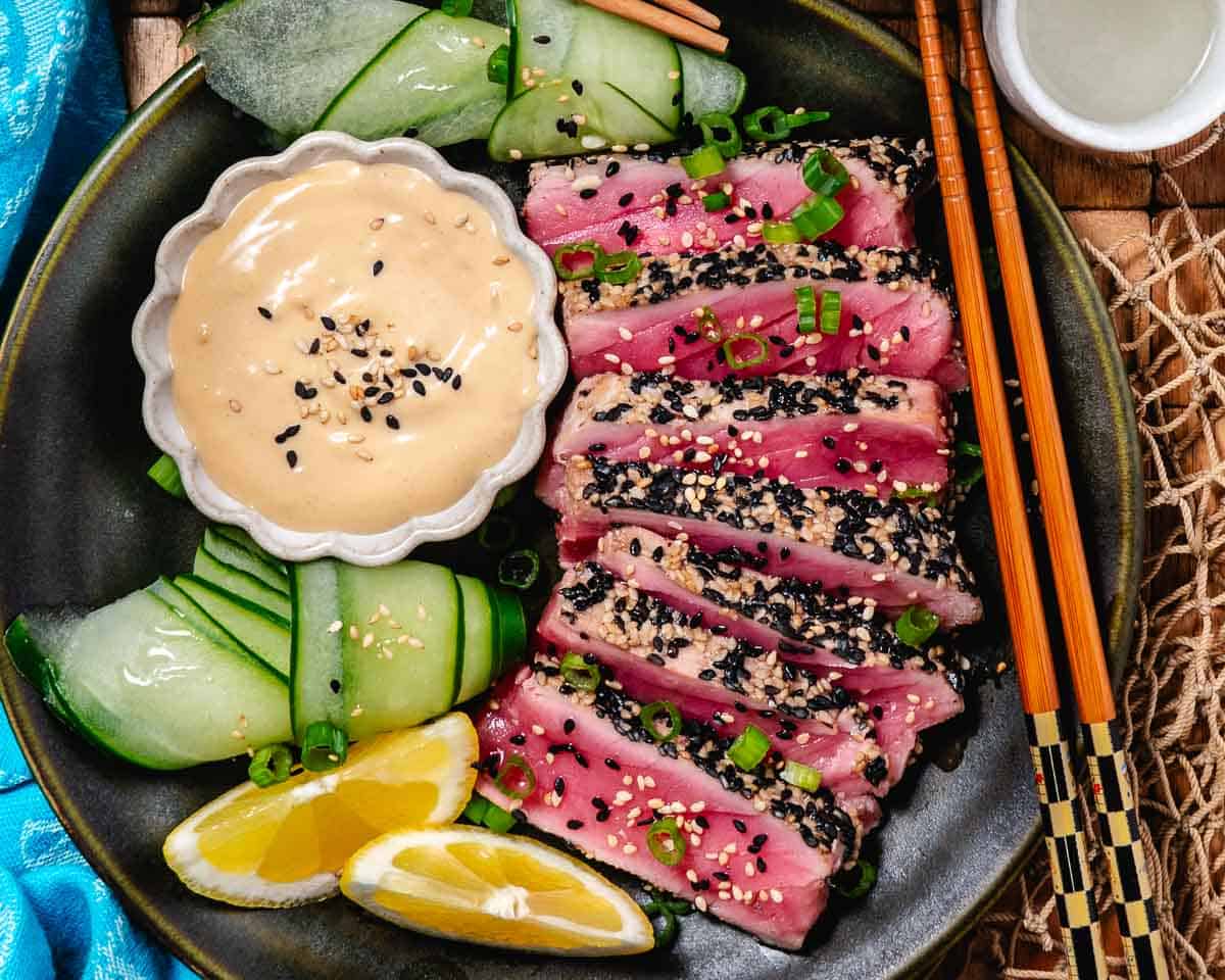 Seared yellowfin tuna with dipping sauce and cucumbers.