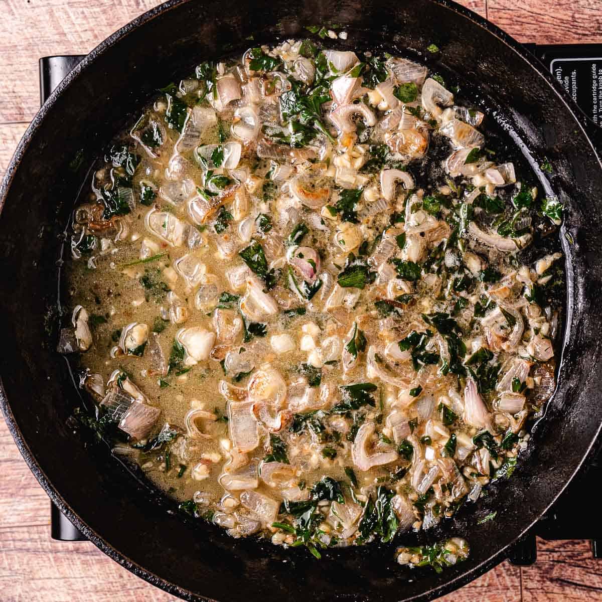 garlic, shallots, and parsley cooking in oil.