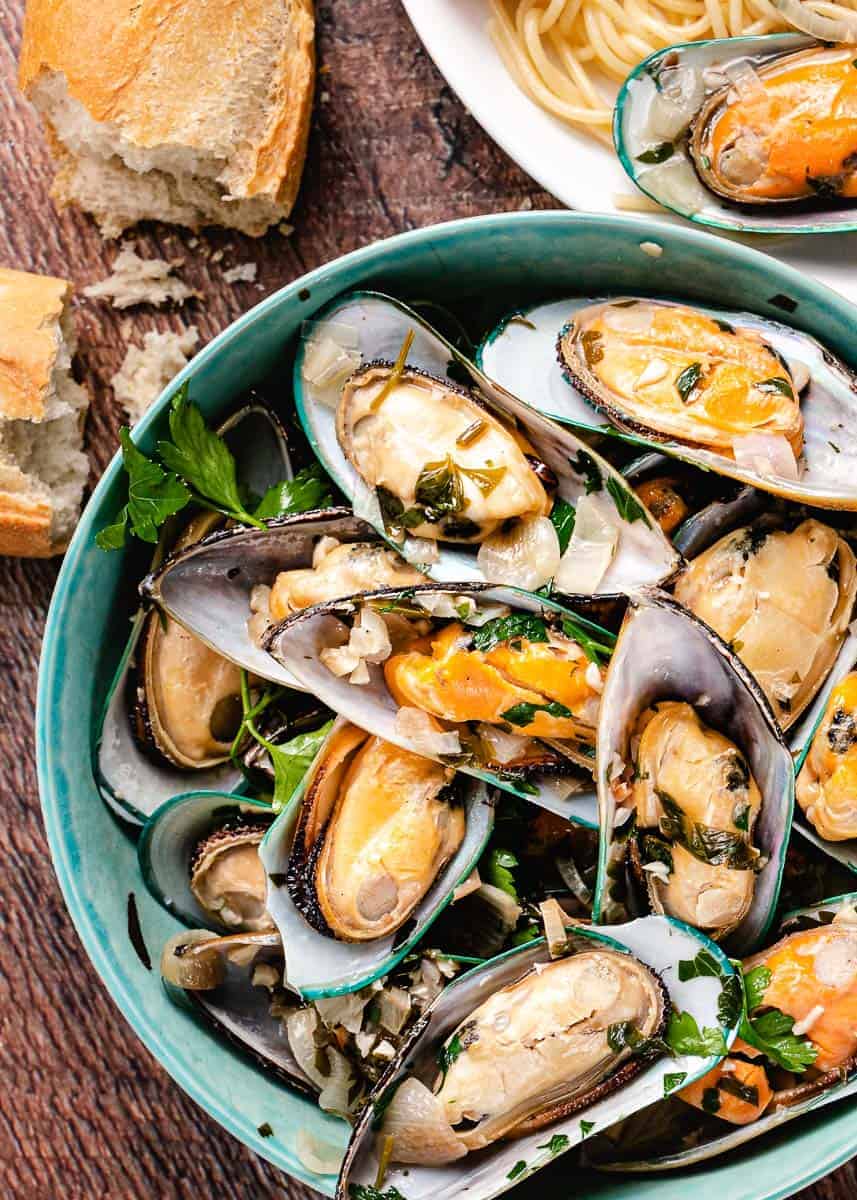 Green mussels in a bowl with bread.