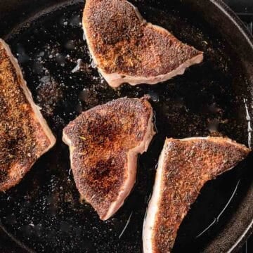 blackened swordfish cooking in cast iron pan.