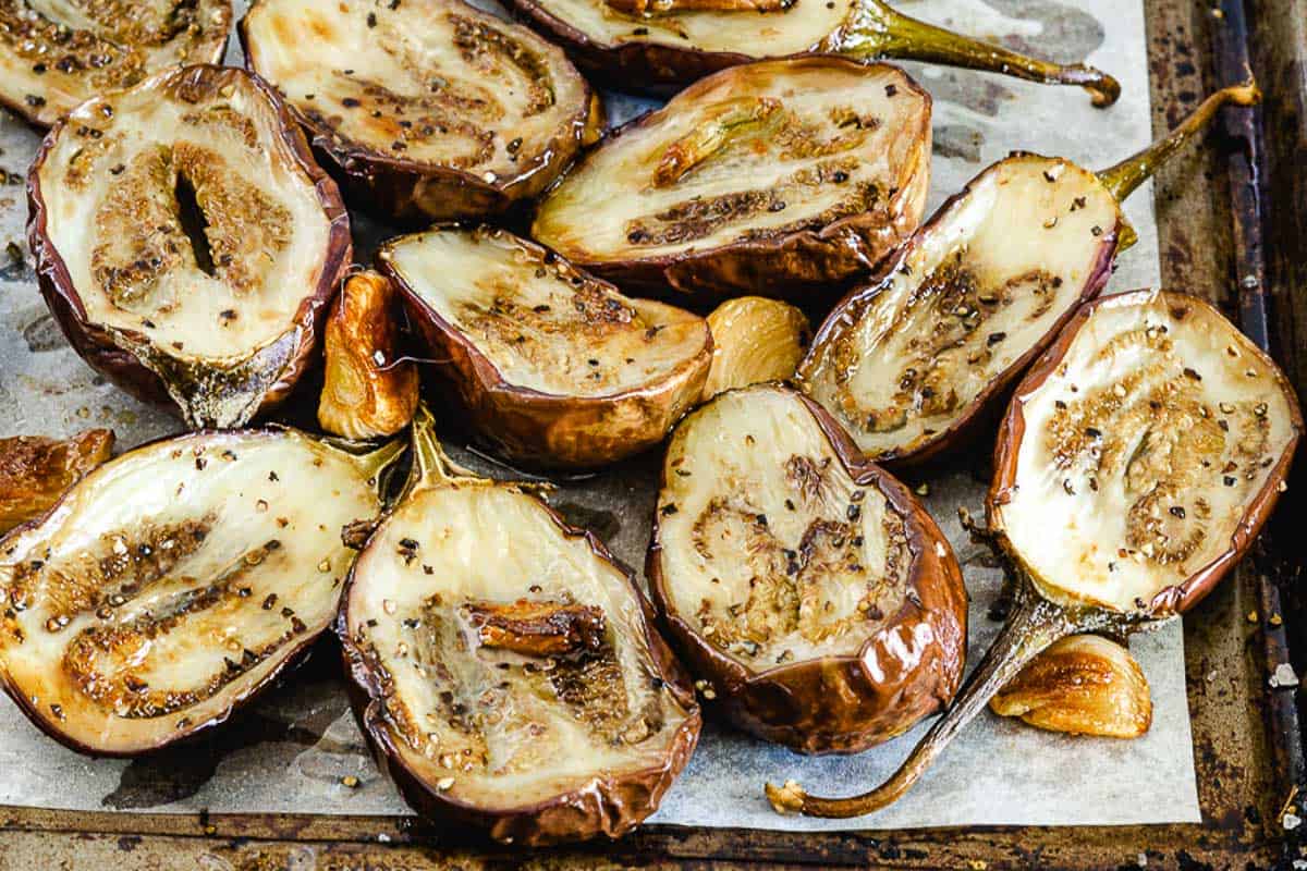 roasted baby eggplant with garlic on a pan.