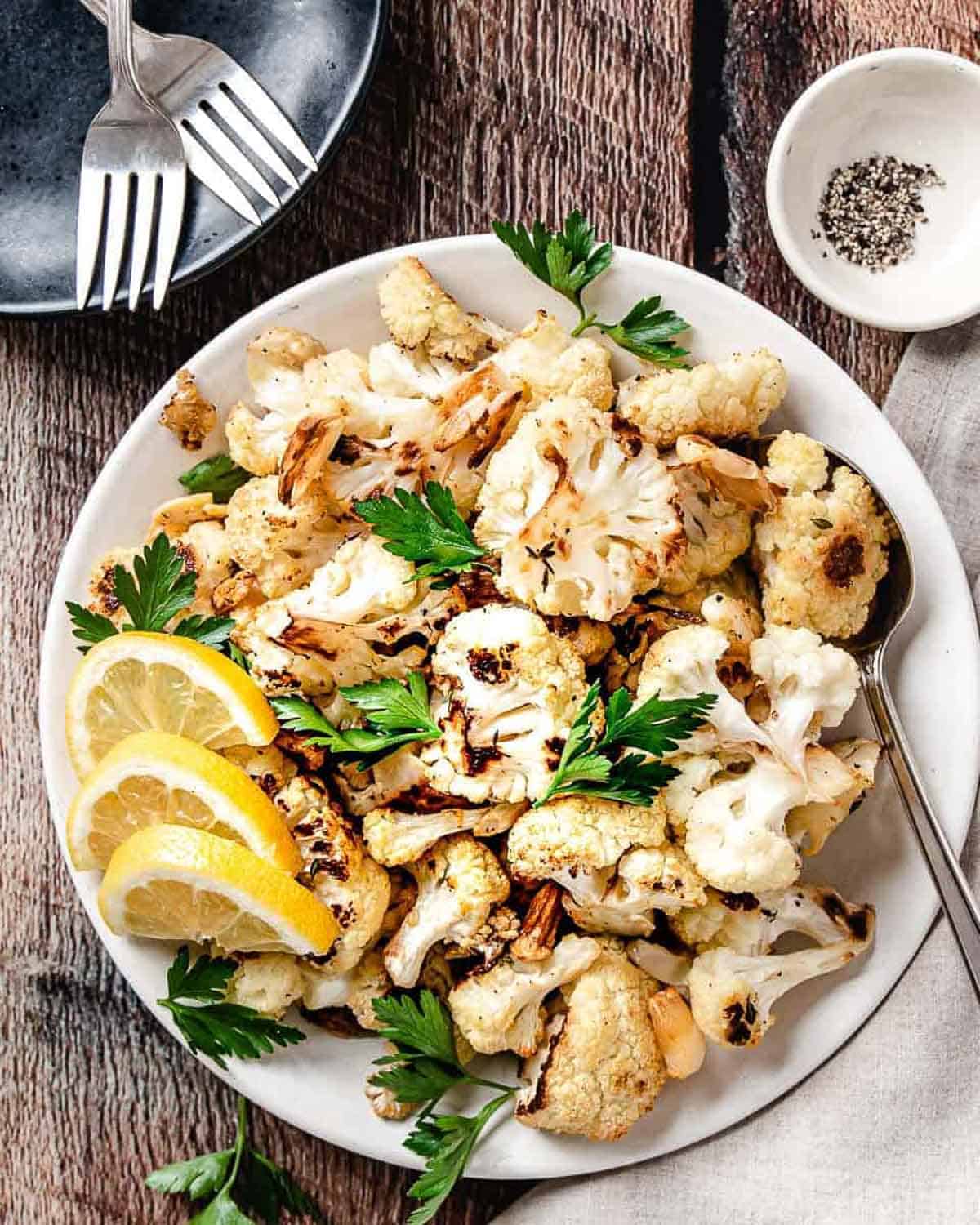 roasted cauliflower with garlic and lemons on a plate.