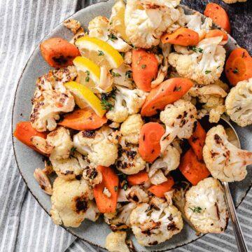 Roasted cauliflower with garlic and carrots on a plate.