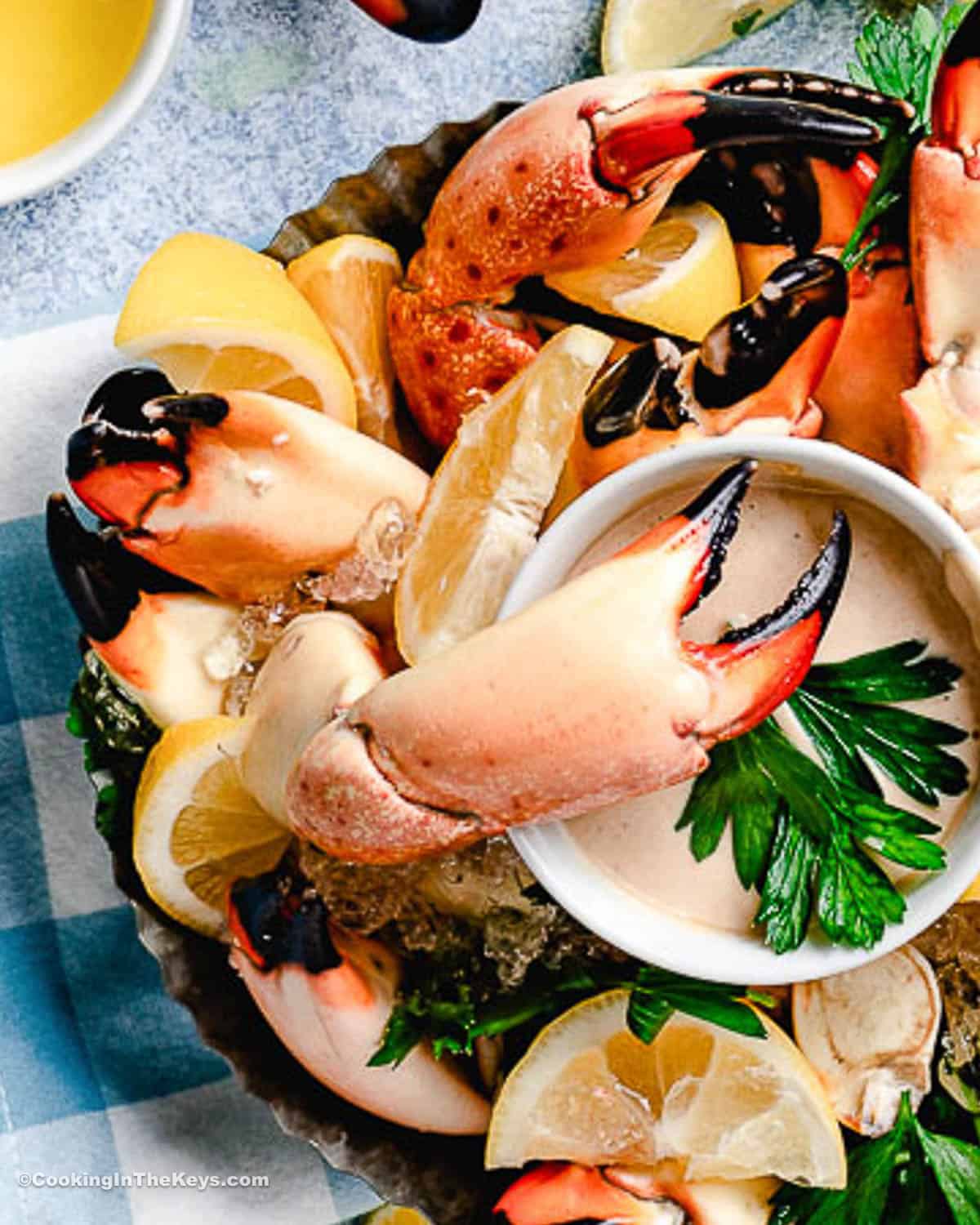 Stone crab claws on a plate with mustard sauce and lemons.