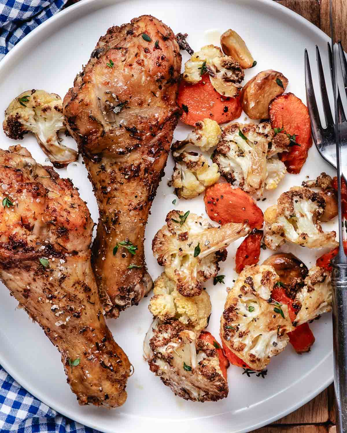 Chicken quarters with cauliflower and carrots with a knife and fork.
