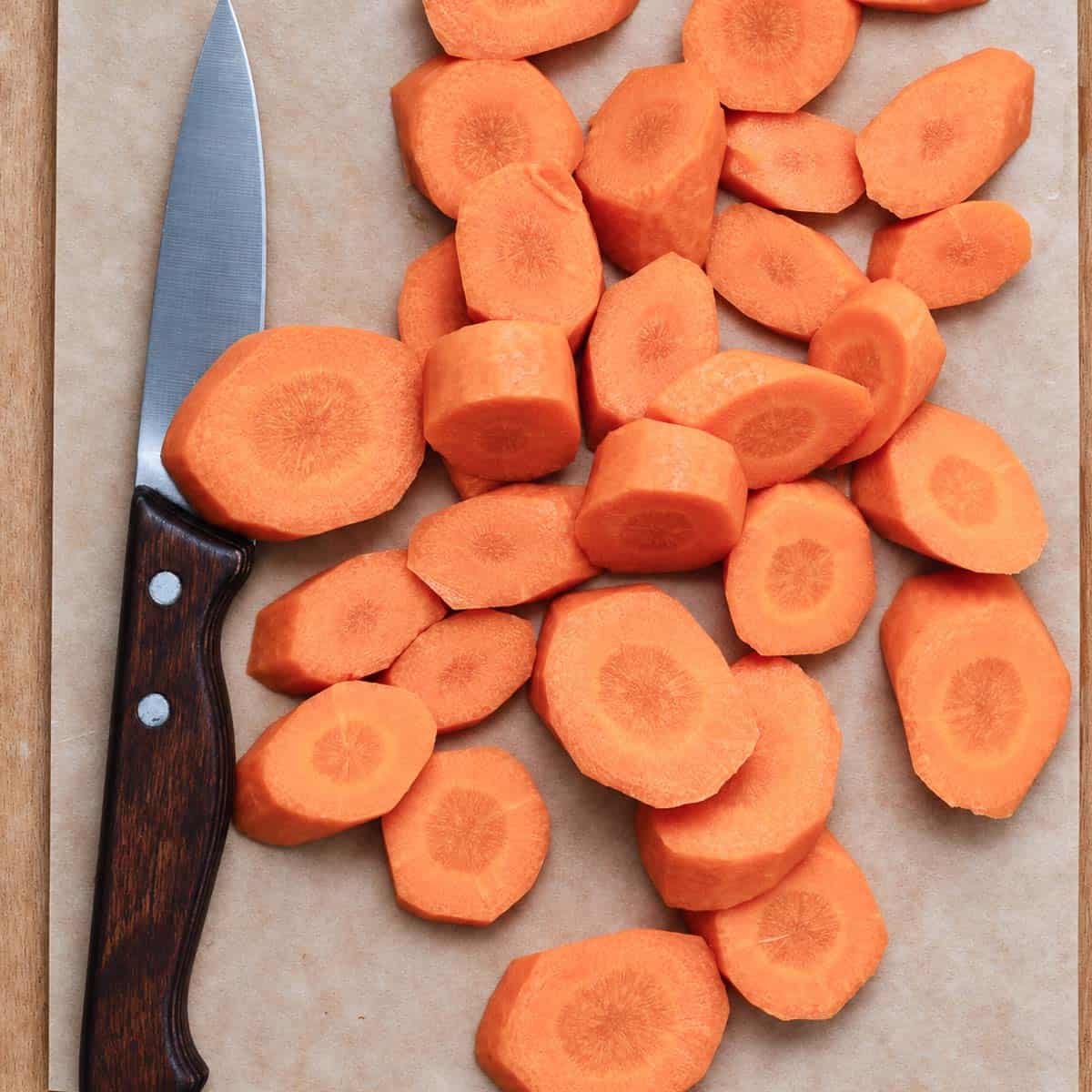 Sliced carrots with a knife on a cutting surface.