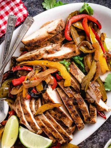 Sliced chicken with onions and peppers on a platter.