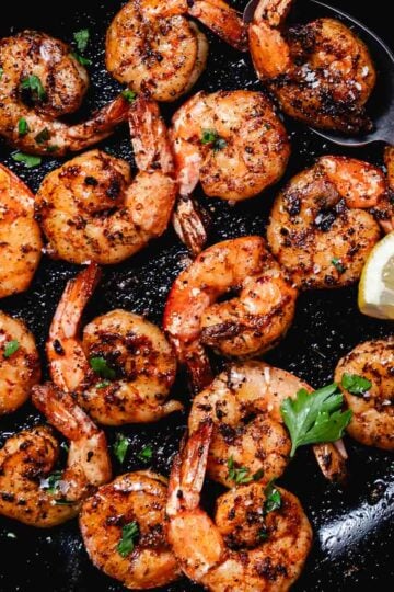 Skillet blackened shrimp with garlic butter, lemon wedges, and fresh parsley.
