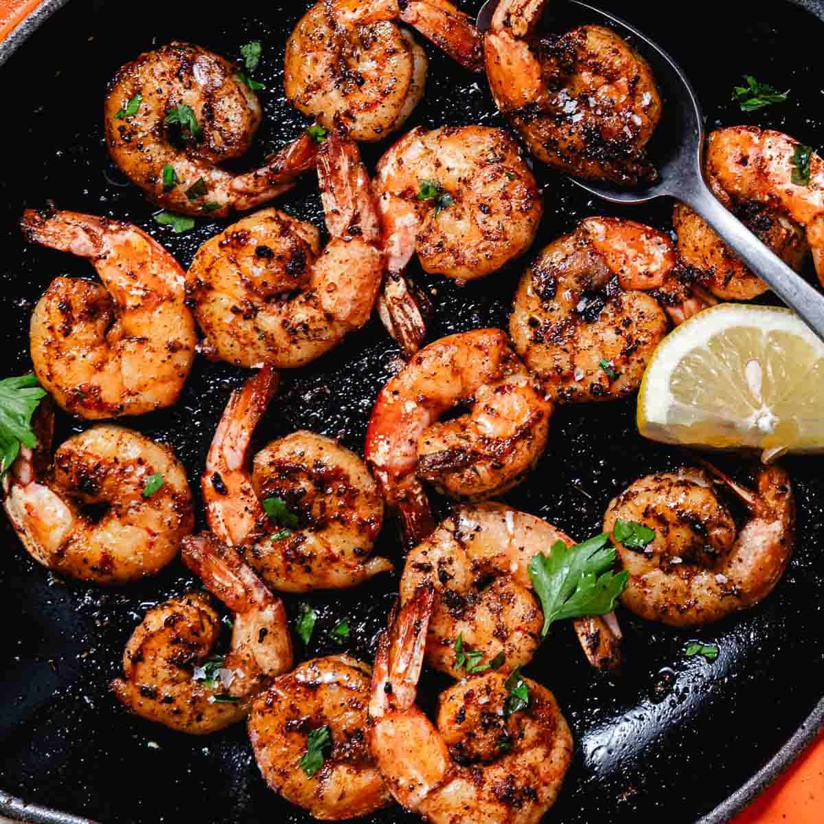 Skillet blackened shrimp with garlic butter, lemon wedges, and fresh parsley.