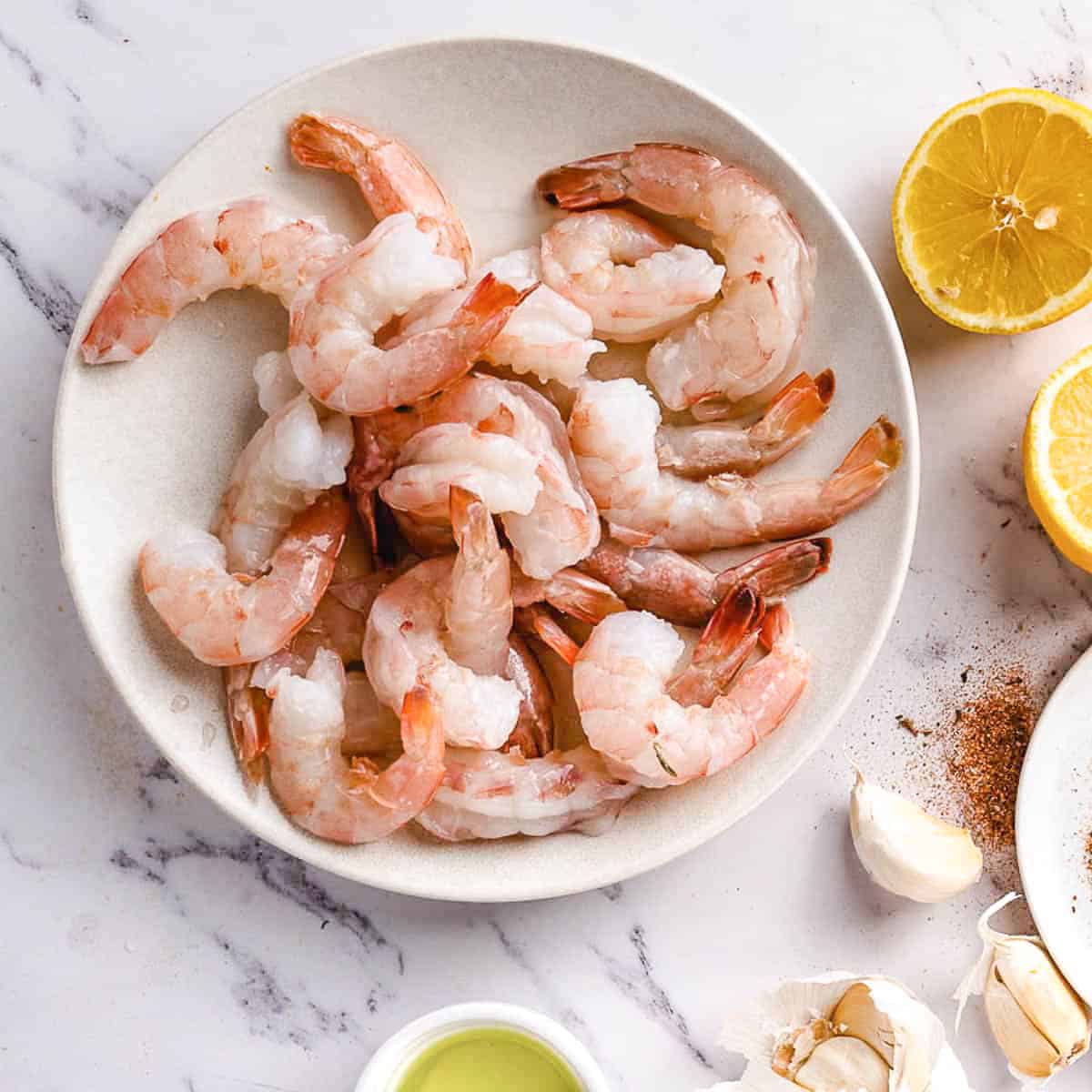 Pink shrimp with lemons on a plate.