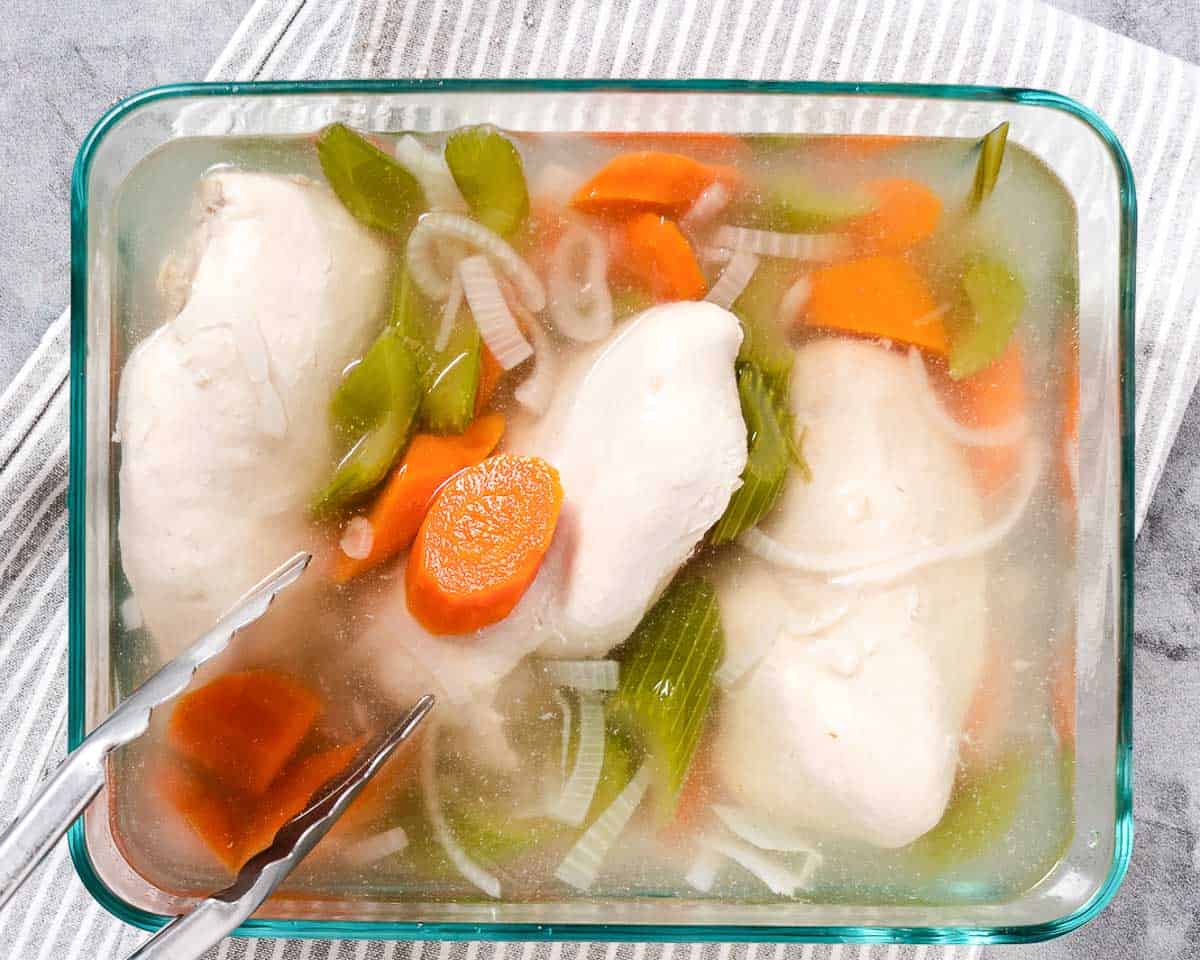 Cooked poached chicken submerged in liquid for storage.