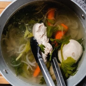poached chicken in a bot with carrots and celery