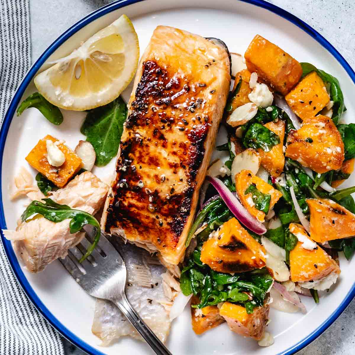 Salmon and sweet potato and arugula salad served with a fork on the side,