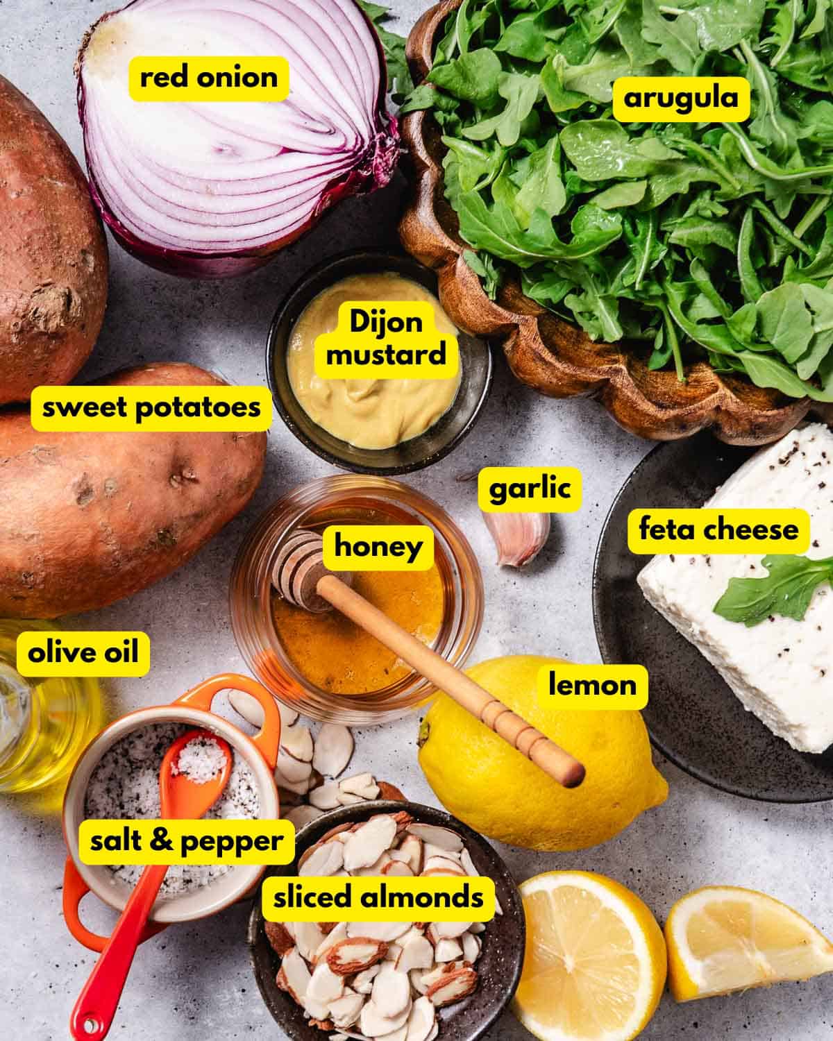 Labeled ingredients for roasted sweet potato arugula salad with feta, almonds, and honey-Dijon dressing.