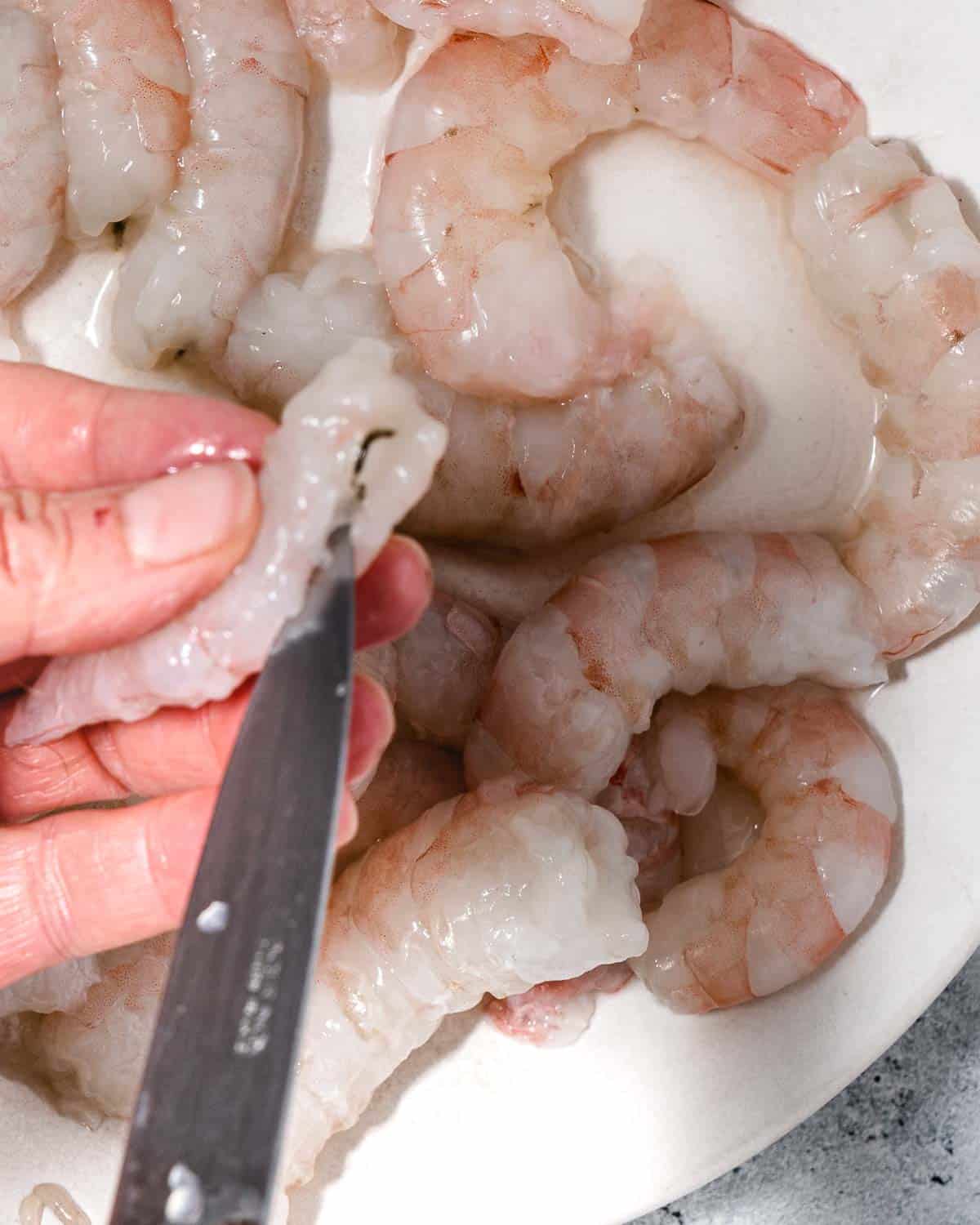 Removing intestinal tract from a shrimp.