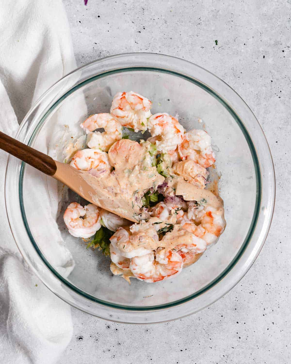 Mixing bowl with shrimp and mayo and rubber spatula.