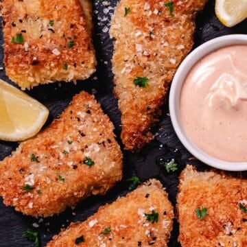 Pan fried red snapper with panko breadcrumbs, lemon wedges, and pink sauce