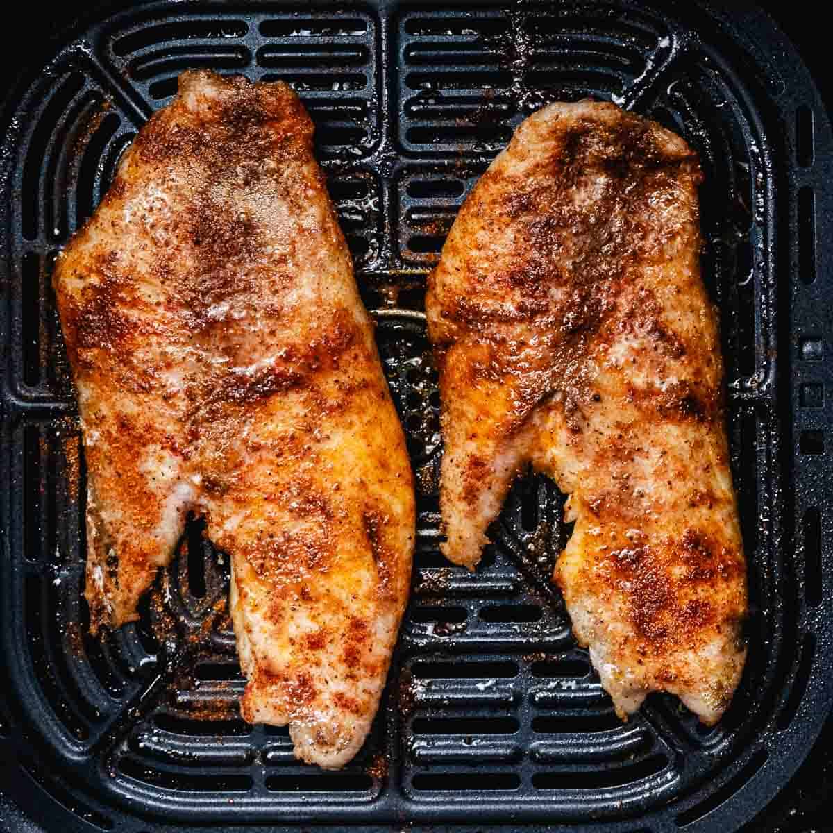 Cooked snapper fillets with Old Bay seasoning in an air fryer basket