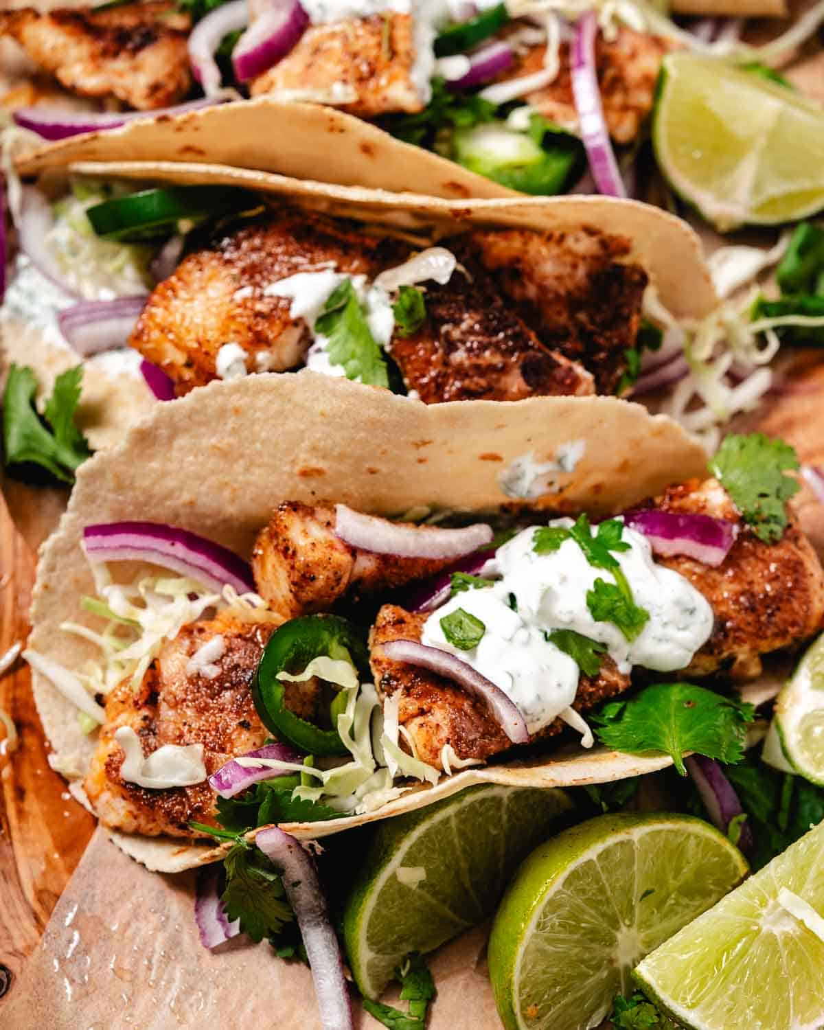 Fish tacos with cream sauce and lime wedges.