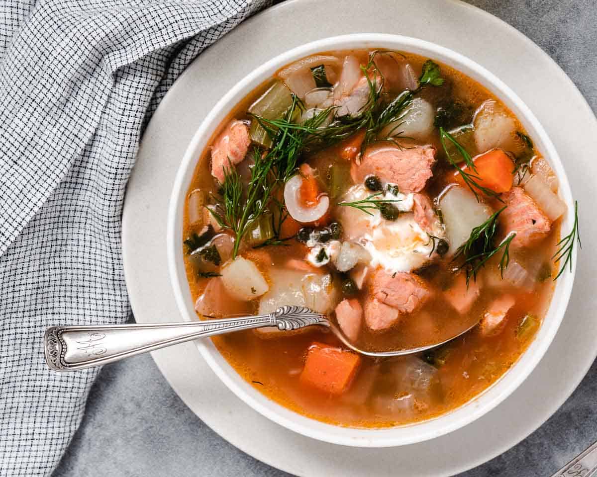 salmon chowder with potatoes and sour cream in a white bowl.