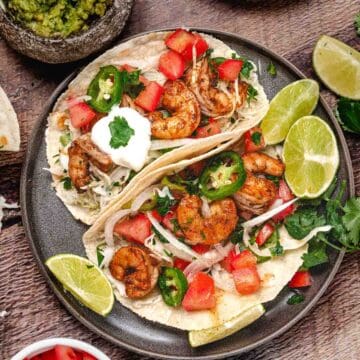 Shrimp tacos with cabbage, tomatoes, and guacamole.