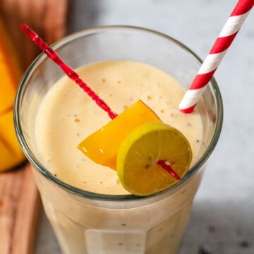 Mango Banana smoothie with red and white straw.