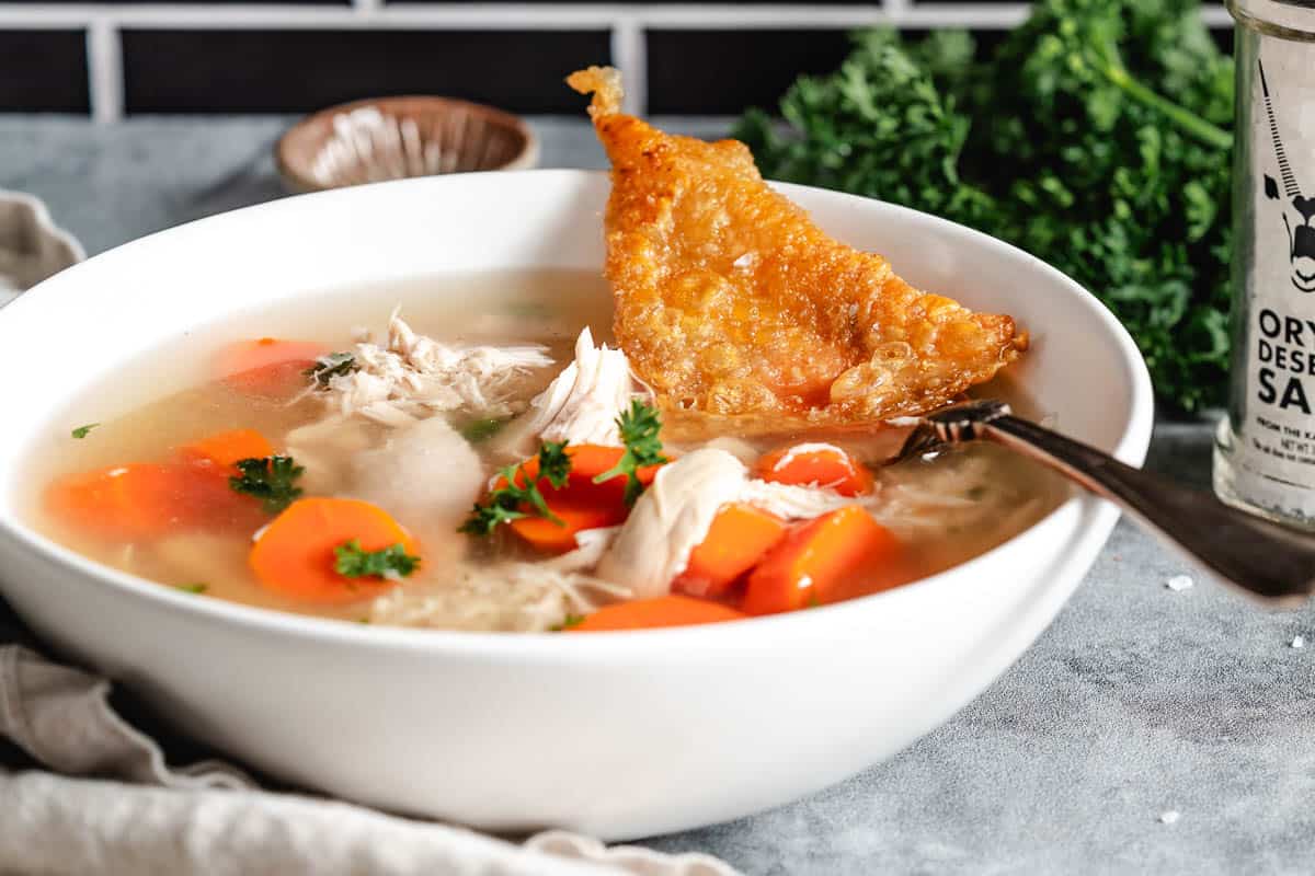 chicken soup with carrots in white bowl.