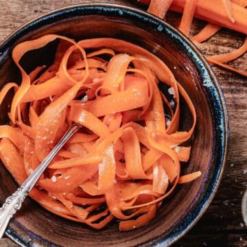 bowl of ray peat's carrot salad with coconut oil, apple cider vinegar and salt in a brown bowl