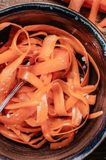 bowl of ray peat's carrot salad with coconut oil, apple cider vinegar and salt in a brown bowl