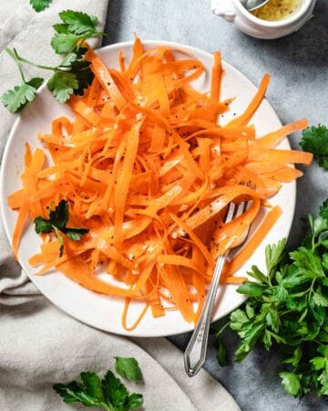 carrot salad with parsley on white plate.
