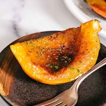 Roasted squash on brown plate with a fork.