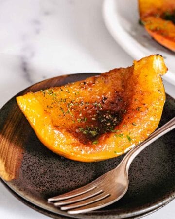 Roasted squash on brown plate with a fork.