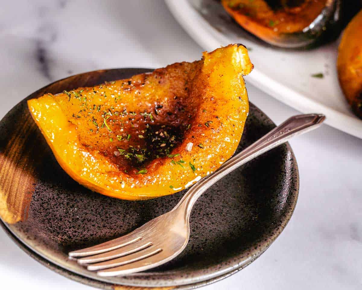 roasted acorn squash on brown plate with fork.