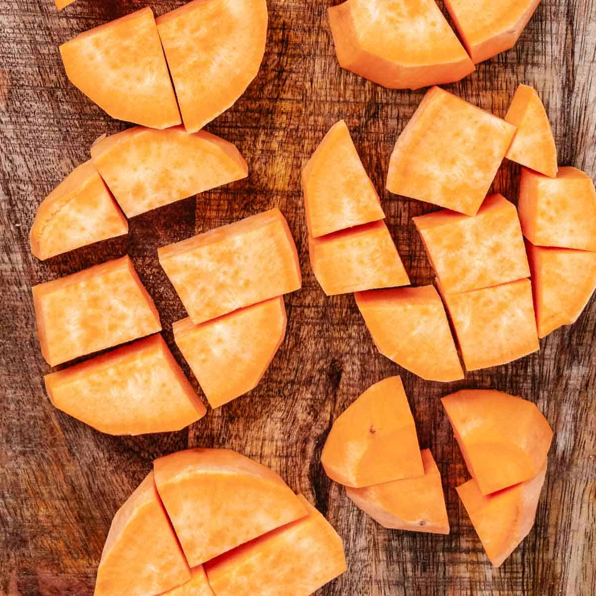 Cubing sweet potatoes on a cutting board.