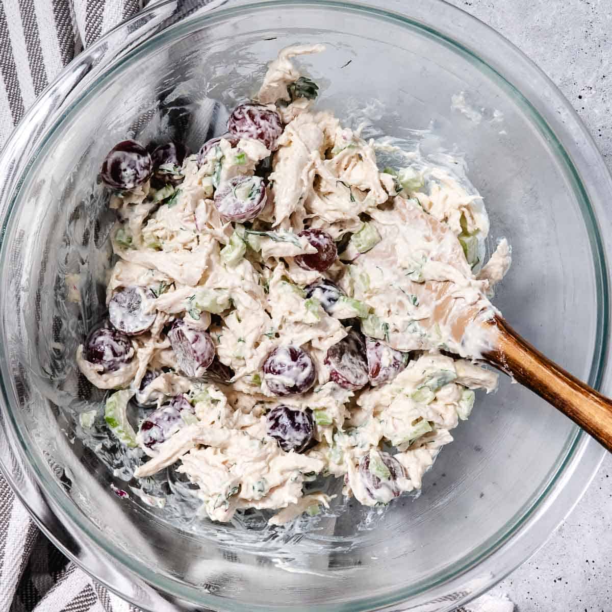mixing bowl with shredded chicken, mayo, mustard, celery, and grapes