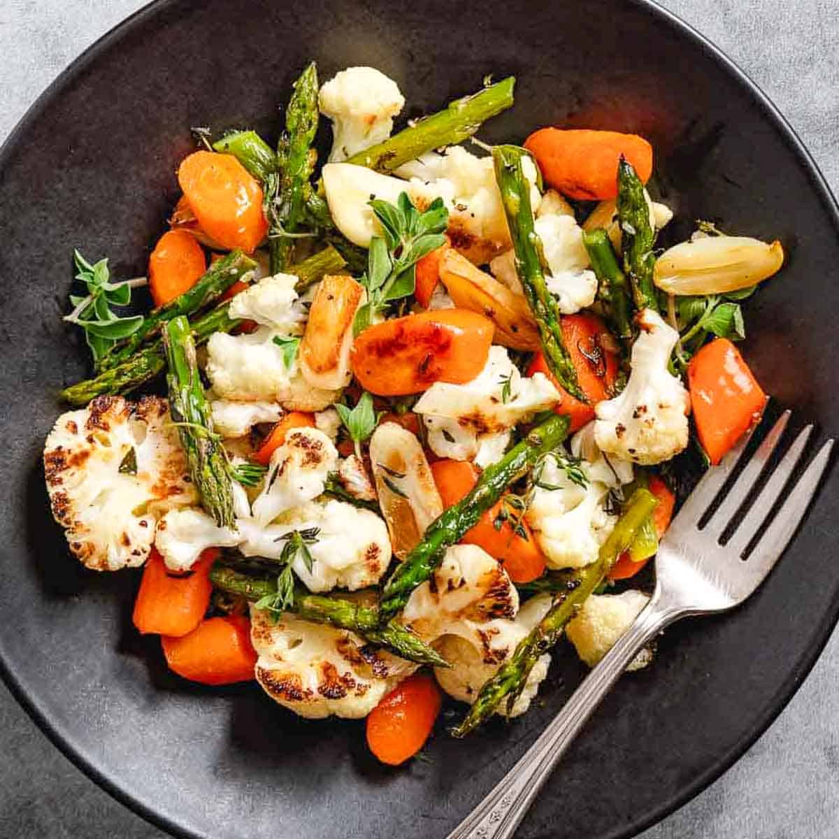 Roasted cauliflower with carrots and asparagus and garlic cloves.