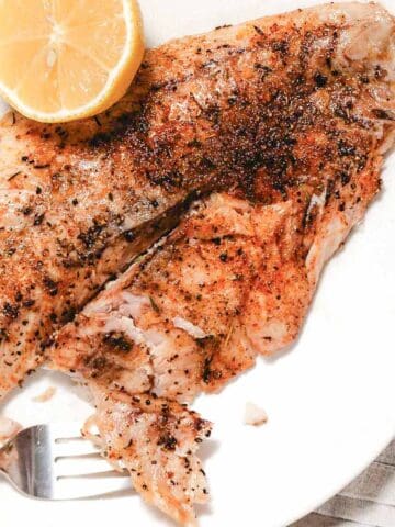 Broiled snapper with lemon on white.