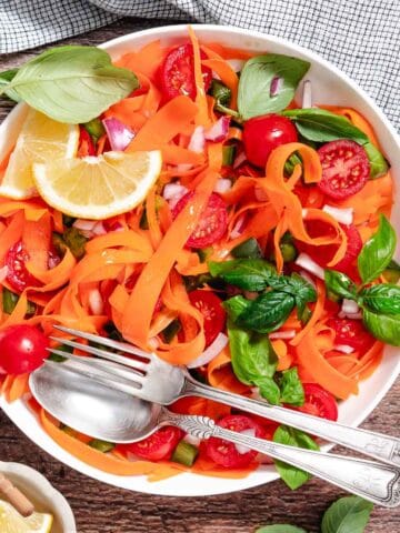 Carrots salad with basil in white bowl.